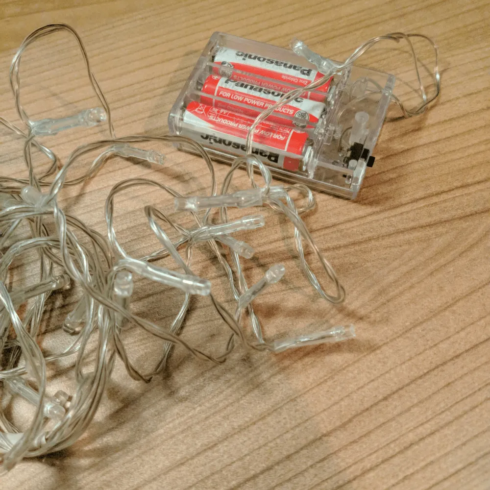 The cheap battery-powered Christmas lights A string of fairy lights with its battery pack holding three AA batteries