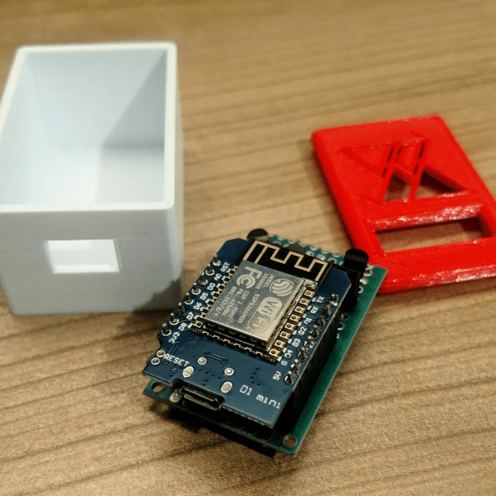 The 3D-printed enclosure A white 3D-printed box and a red lid with a cut-out logo, next to the assembled controller