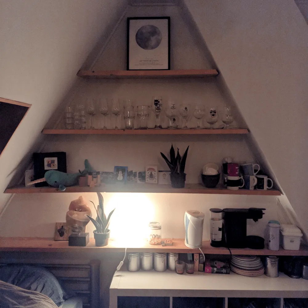 Before: one Ikea lamp, a little too bright Triangular wall shelves lit only by a single bright lamp on the bottom shelf